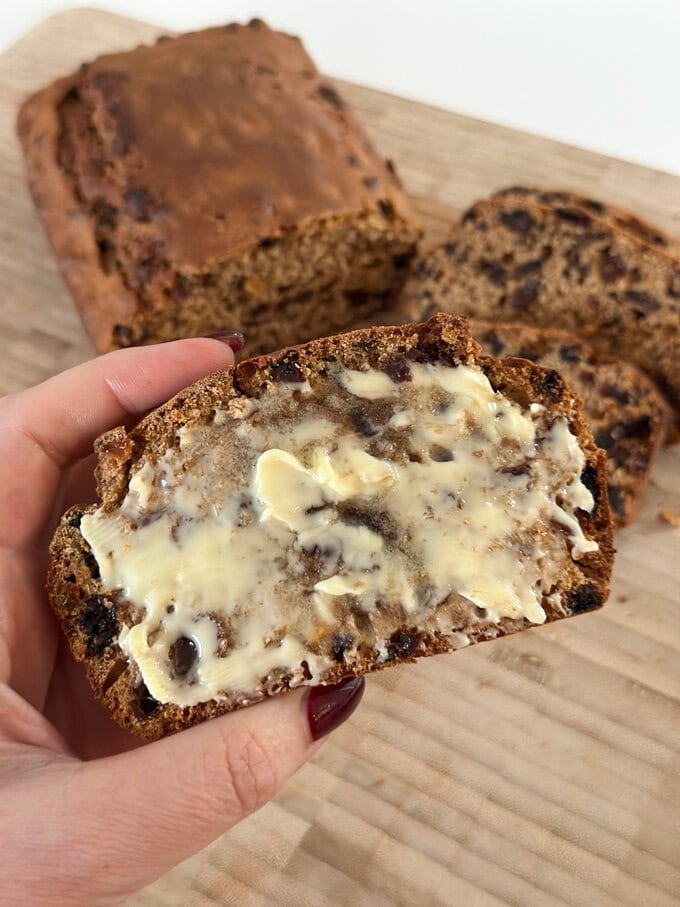 A slice of Irish Barmbrack covered with butter.