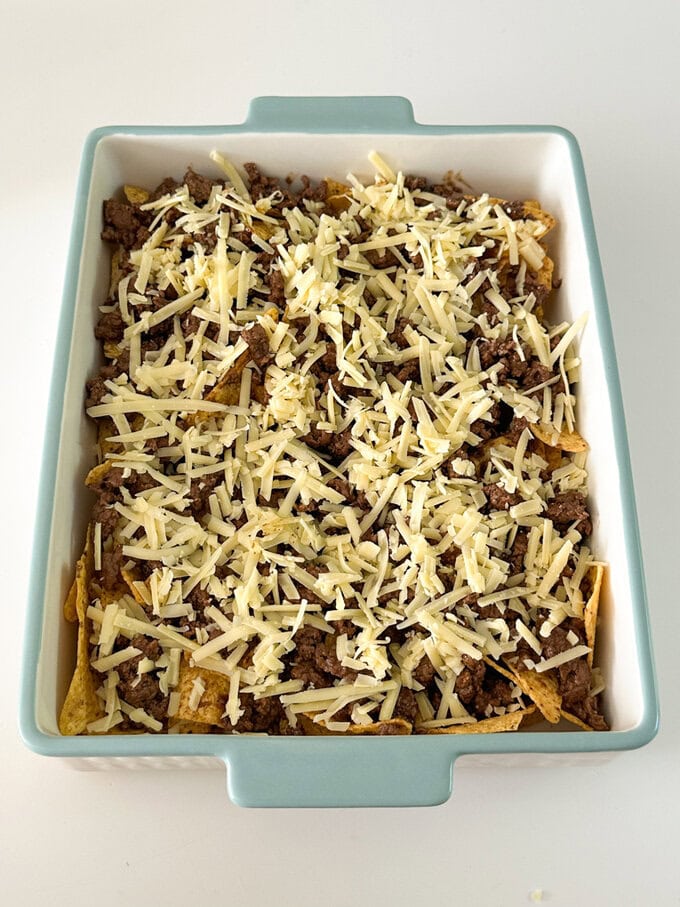 Tortilla chips cover in Nacho mince and grated cheese added ready for melting.