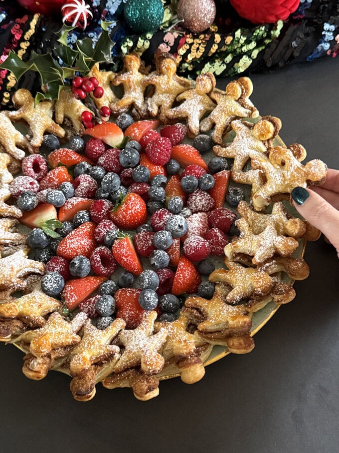Gingerbread man puff pastry wreath presented with fresh berries and dusted in icing sugar.