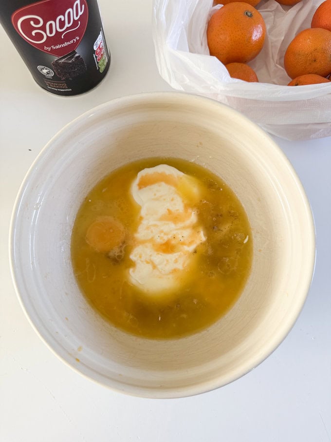 Ingredients being added to a cream colored mixing bowl.