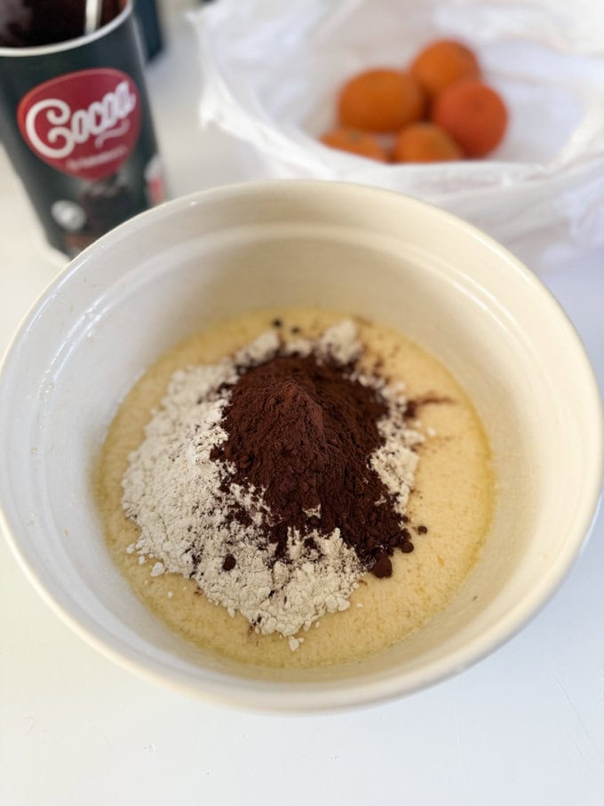 Ingredients being added to a cream colored mixing bowl.