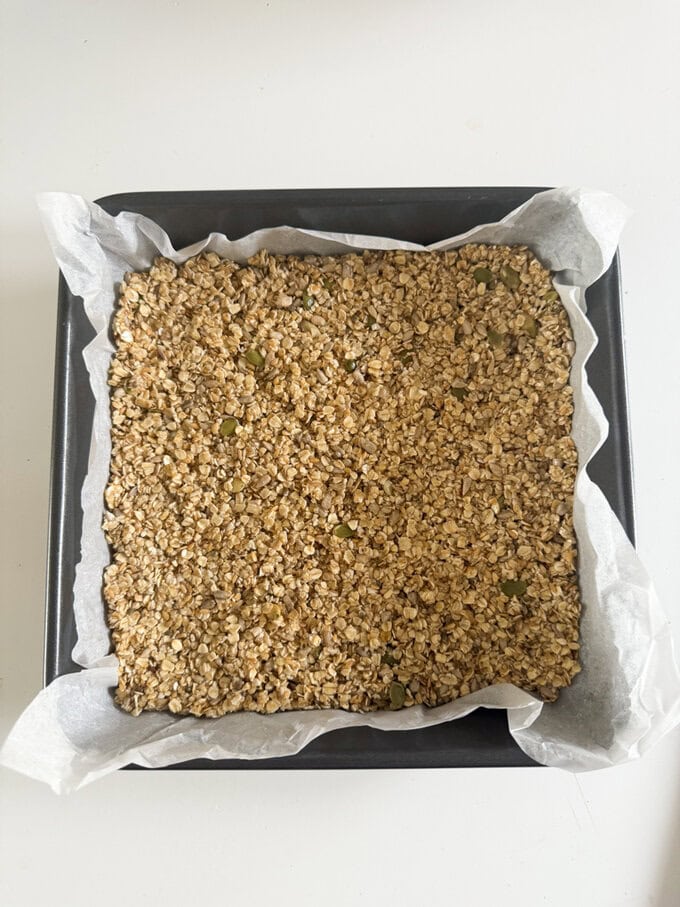 Nut free flapjack in a oven dish with grease proof paper ready for the oven.