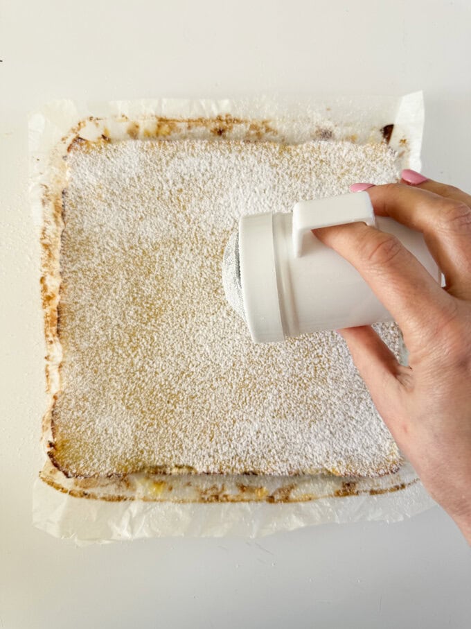 Icing sugar being dusted over the lemon bars.