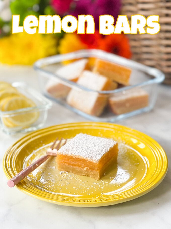 A Square lemon bar on a yellow Le Creuset plate with a small cake fork balanced on the plate next to it.