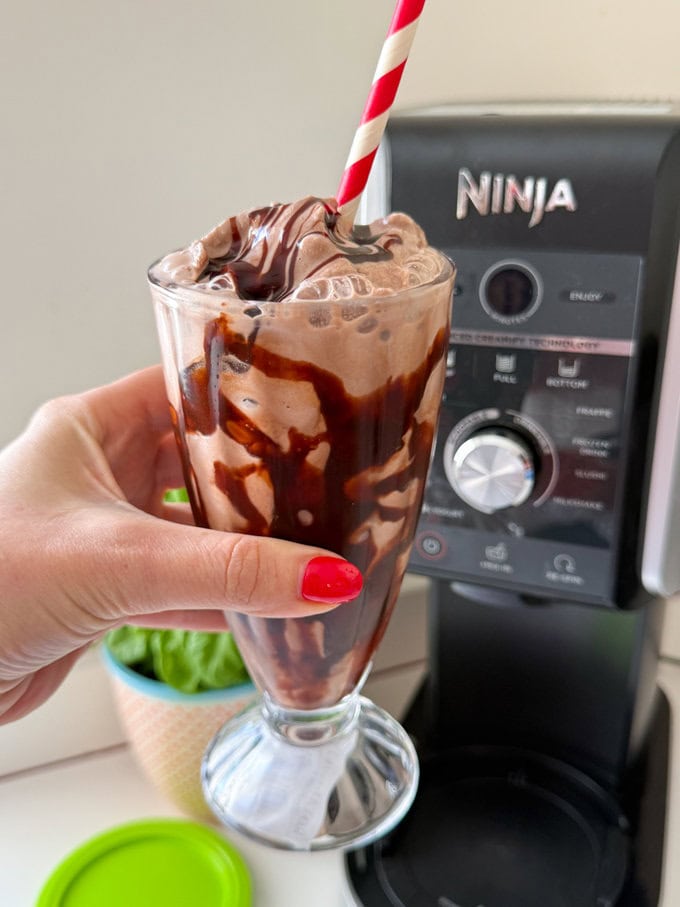 Ninja Creami Chocolate Milkshake served in a tall clear milkshake glass with a red and white striped straw.