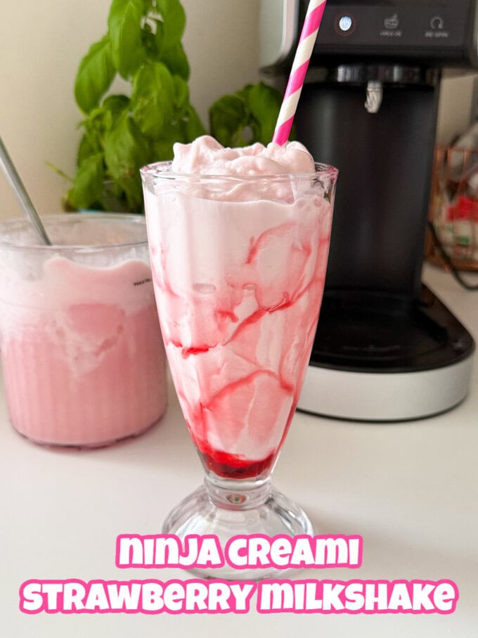 A strawberry milkshake in an old fashioned tall milkshake glass with a pink and white striped straw in it.