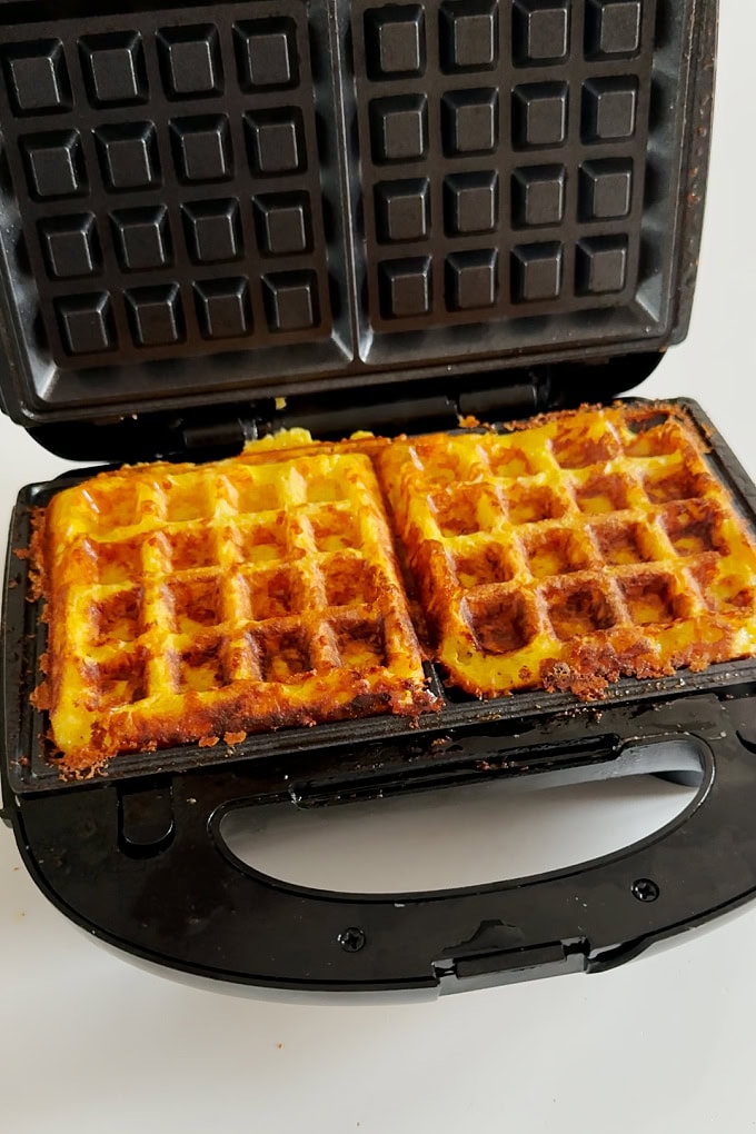 Cheesy Carrot Waffles being made in a waffle maker.