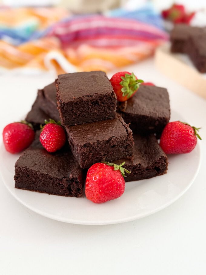 A big stack of Chocolate cake bars served with whole strawberries.