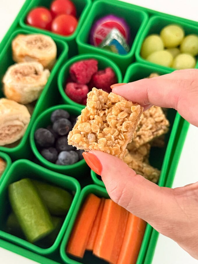 Mini No Bake Granola Bites served in a bright green kids snackle box along with lots of other tasty snacks.