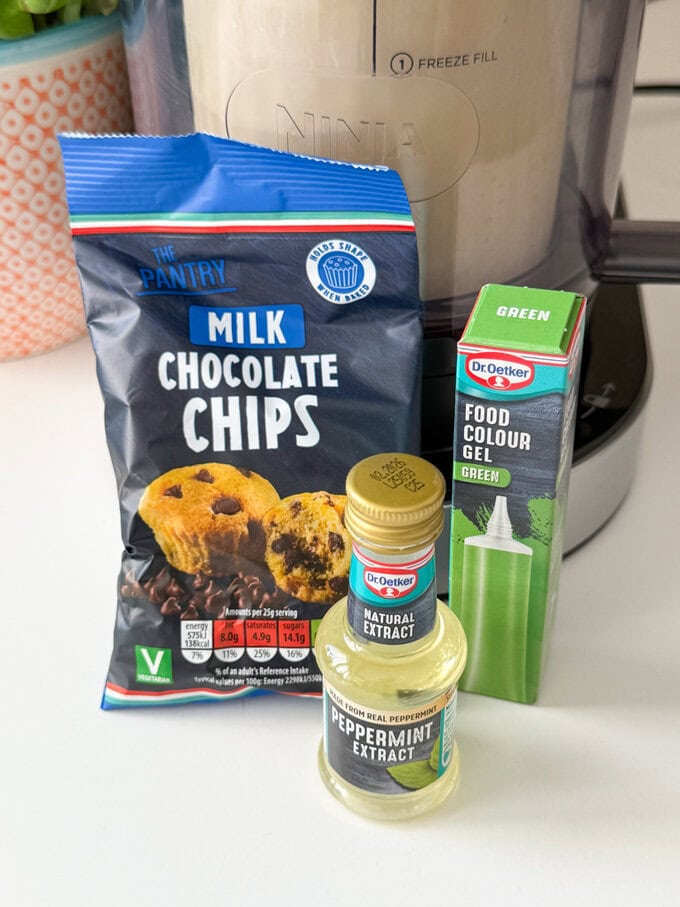 Ingredients for Homemade Mint Choc Chip Ice Cream made in the Ninja Creami laid out on a kitchen worktop.