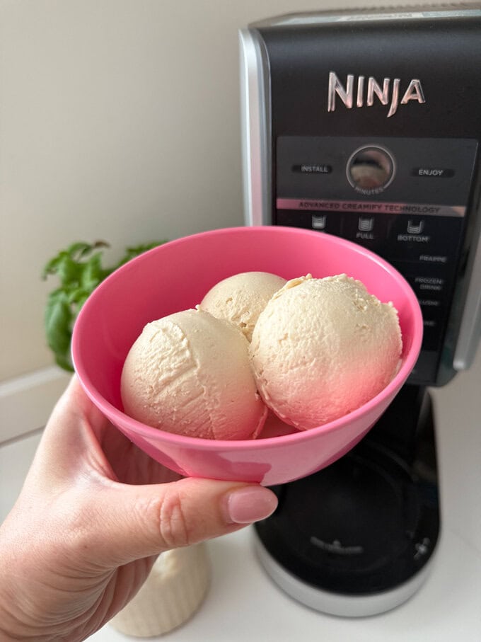 Frozen yogurt made in the Ninja Creami with peanut butter and banana, served in a bright pink ice cream bowl.