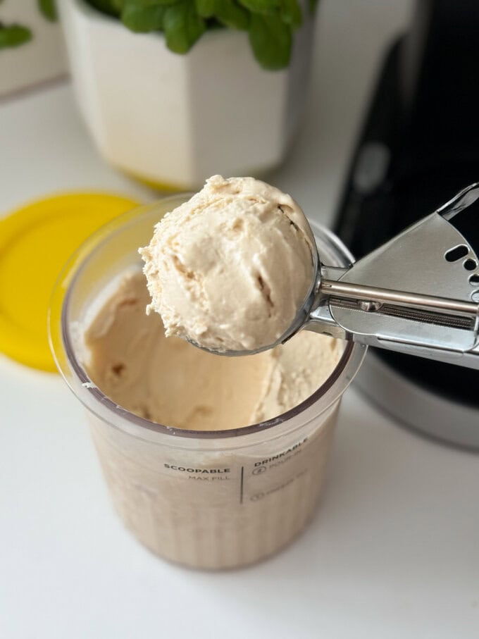 Frozen yogurt made in the Ninja Creami with peanut butter and banana being served using a stainless steel ice cream scoop.