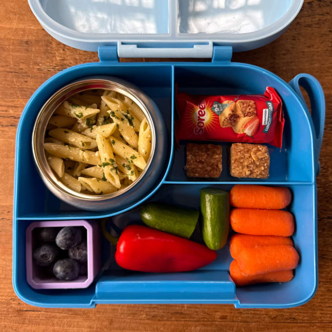 Nut Free Pesto Pasta served in a bright blue hot & cold lunchbox, served with chopped fresh veggies.